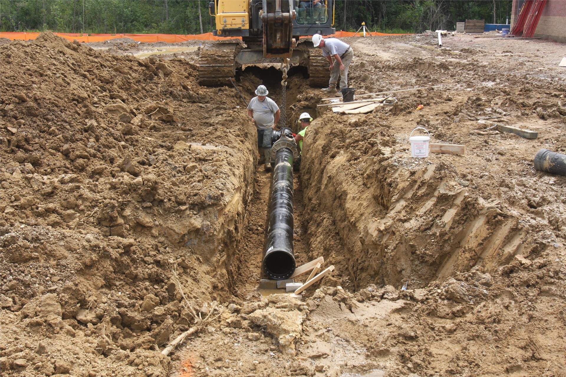 Construction workers installing pipelines in the ground under location of parking lot