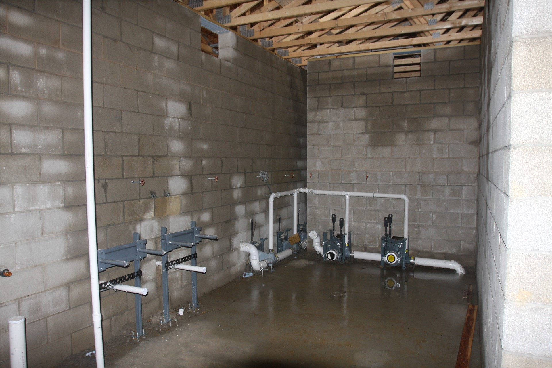 Plumbing for showers and restrooms inside locker rooms on visitor side of stadium building