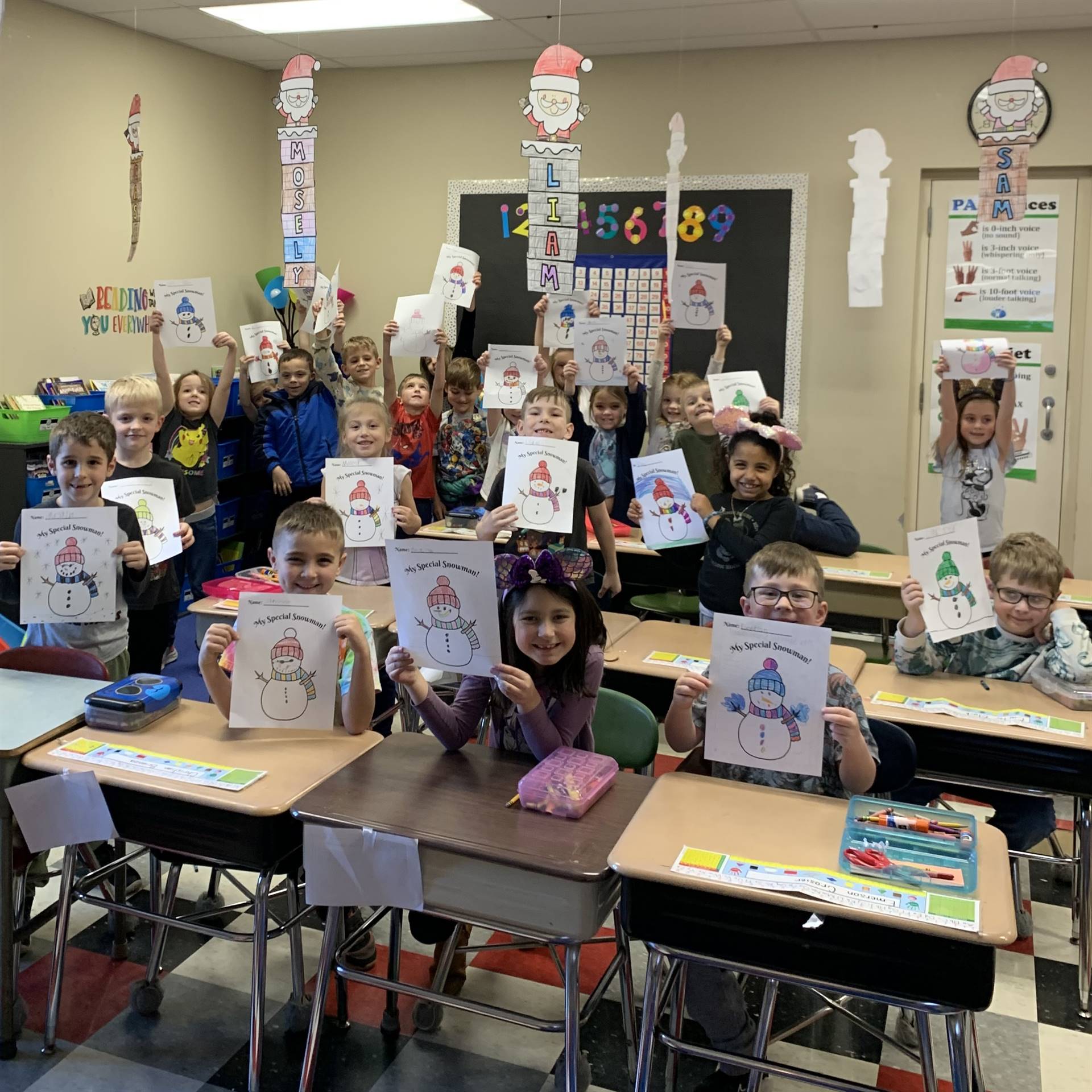 Students holding up snowmen that they colored.