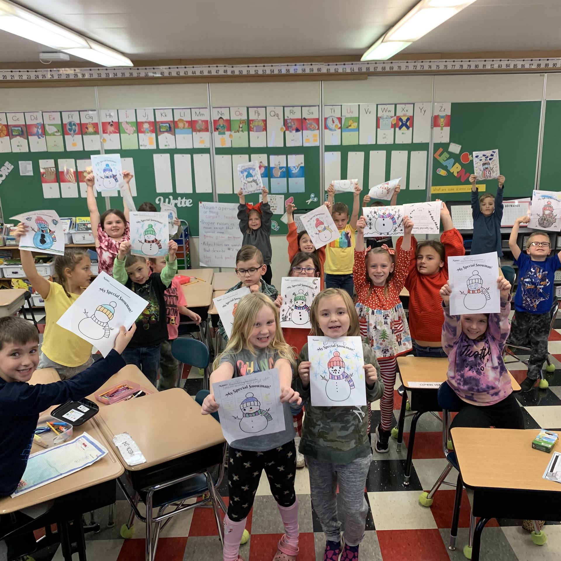 Students holding up snowmen that they colored.