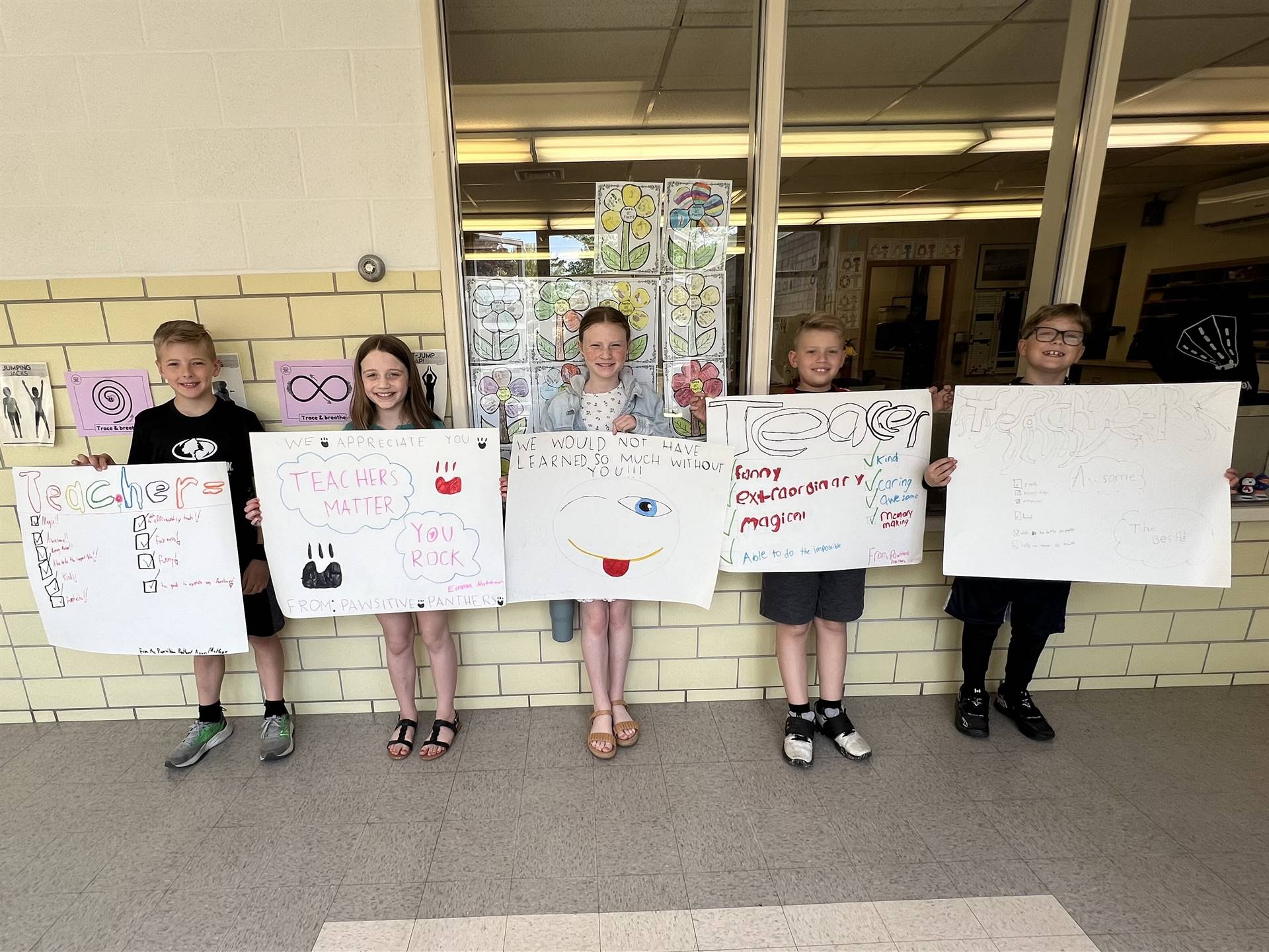 4th grade students holding homemade teacher appreciation posters